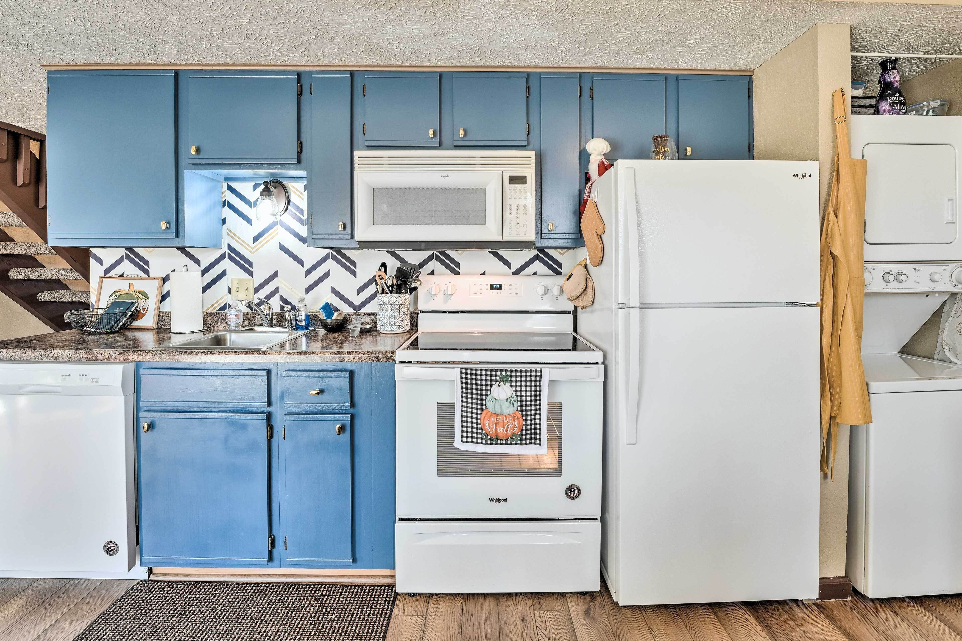 Une cuisine avec des armoires bleues, un réfrigérateur blanc, un four à micro-ondes et une cuisinière.