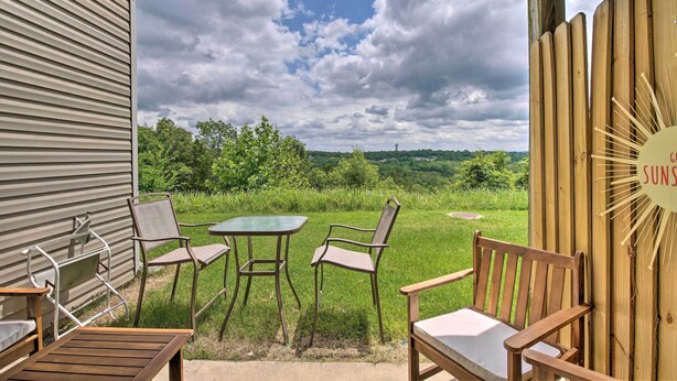 An outdoor seating area with a table and chairs, a wooden bench, and a view of a green landscape with trees and a cloudy sky. - Cheerful Condo: Patio, 2 Mi to Branson Strip! (Branson)