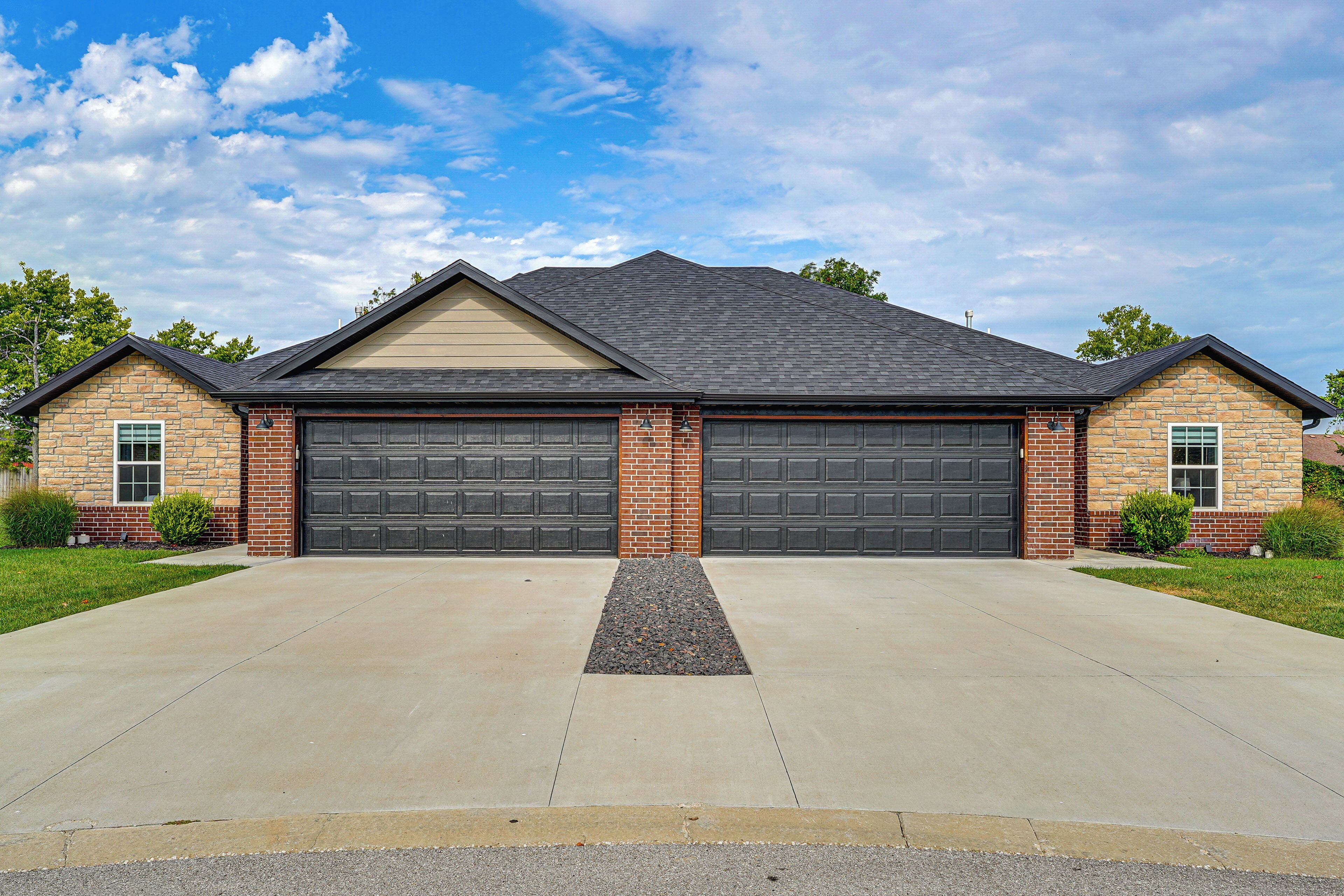 A two-story house with a garage, a driveway, and a well-maintained lawn.