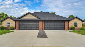 A two-story house with a garage, a driveway, and a well-maintained lawn.