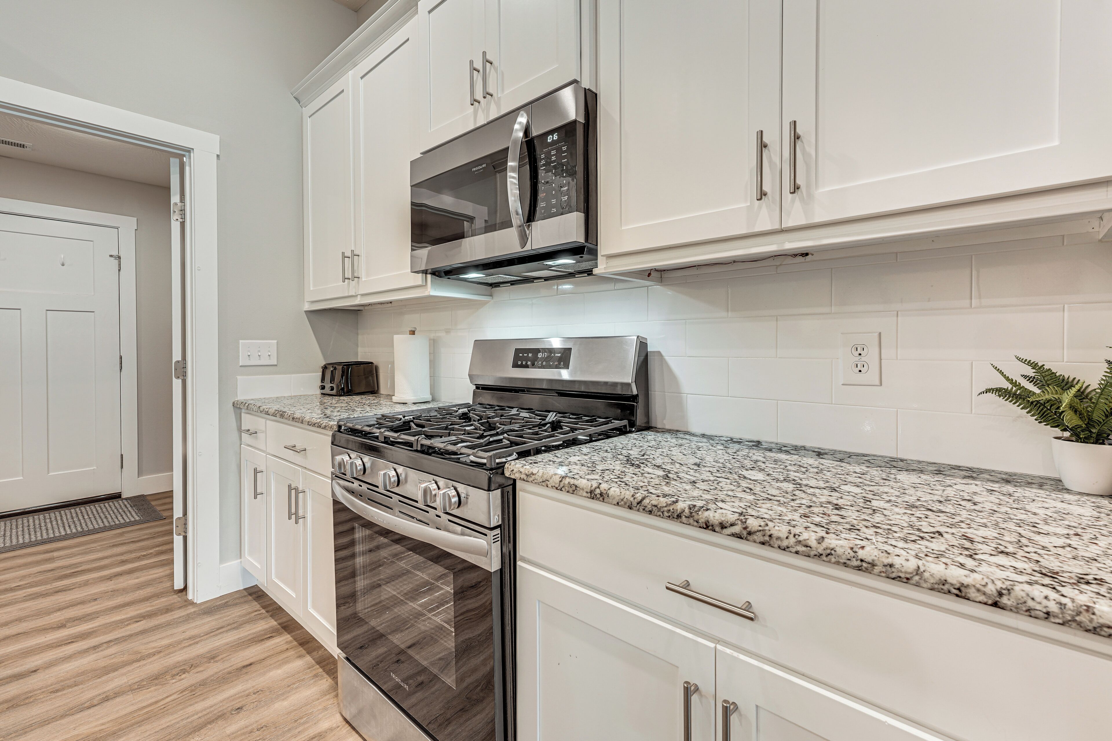A modern kitchen with white cabinetry, stainless steel appliances, and a granite countertop.