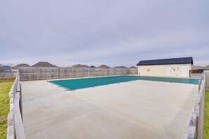 A backyard with a swimming pool, a wooden fence, and a small shed. - Charming Ozark Abode w/ Yard & Pool Access (Ozark)