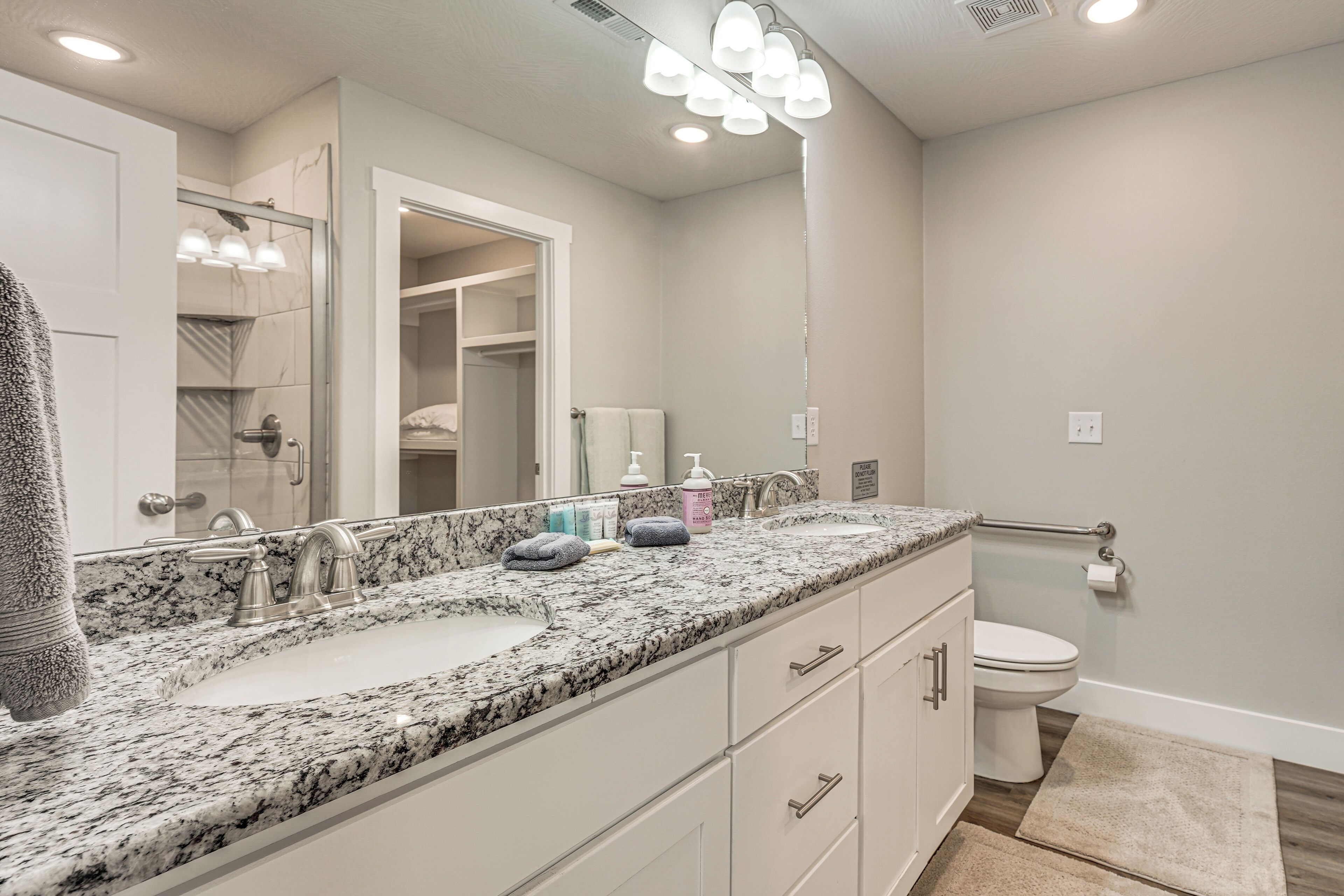 A bathroom with a double sink vanity, a toilet, and a shower area.