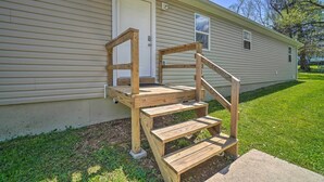 Un escalier en bois mène à la porte d’entrée d’une maison de plain-pied dotée d’un petit porche.