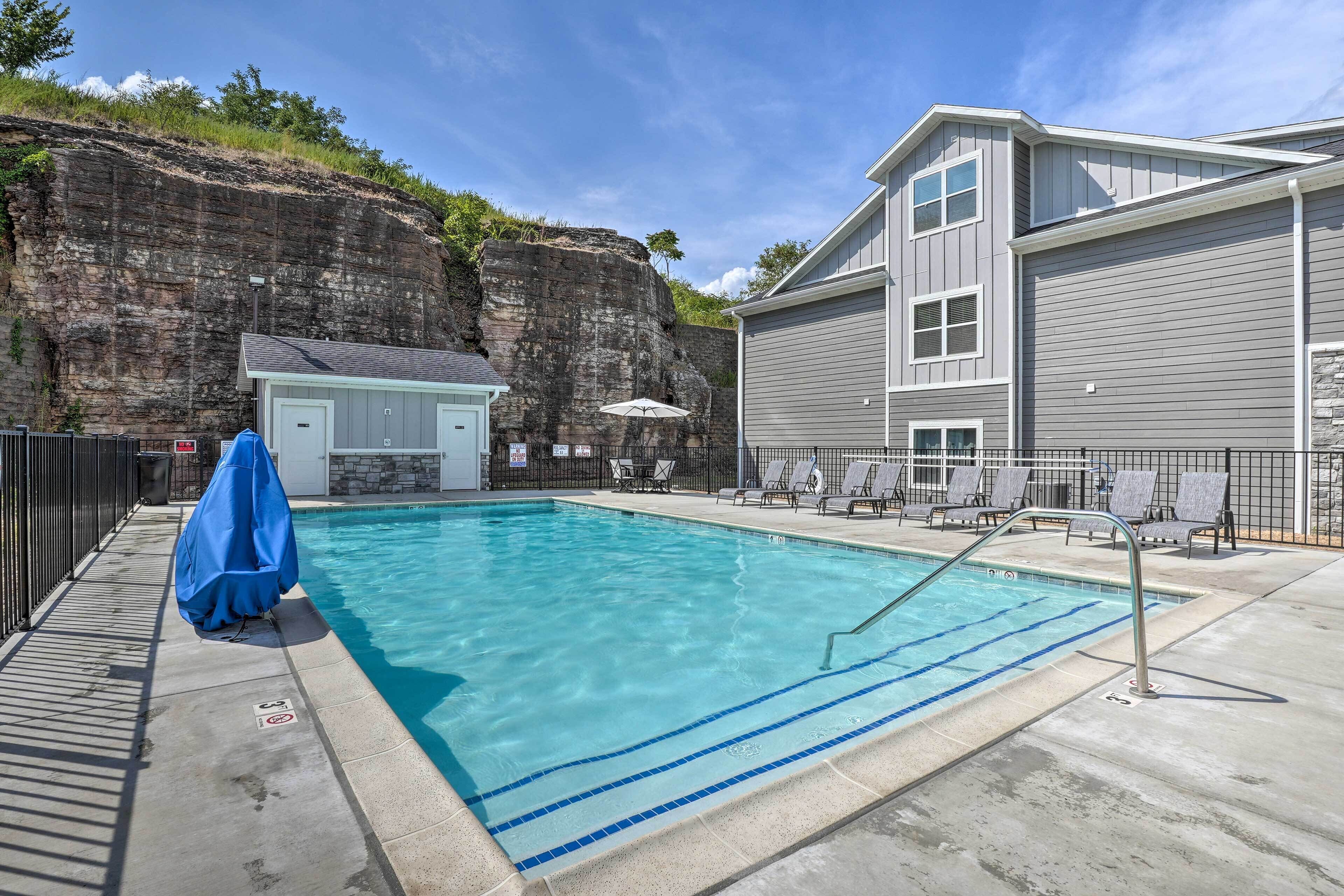 A swimming pool with a diving board, lounge chairs, and a covered area.