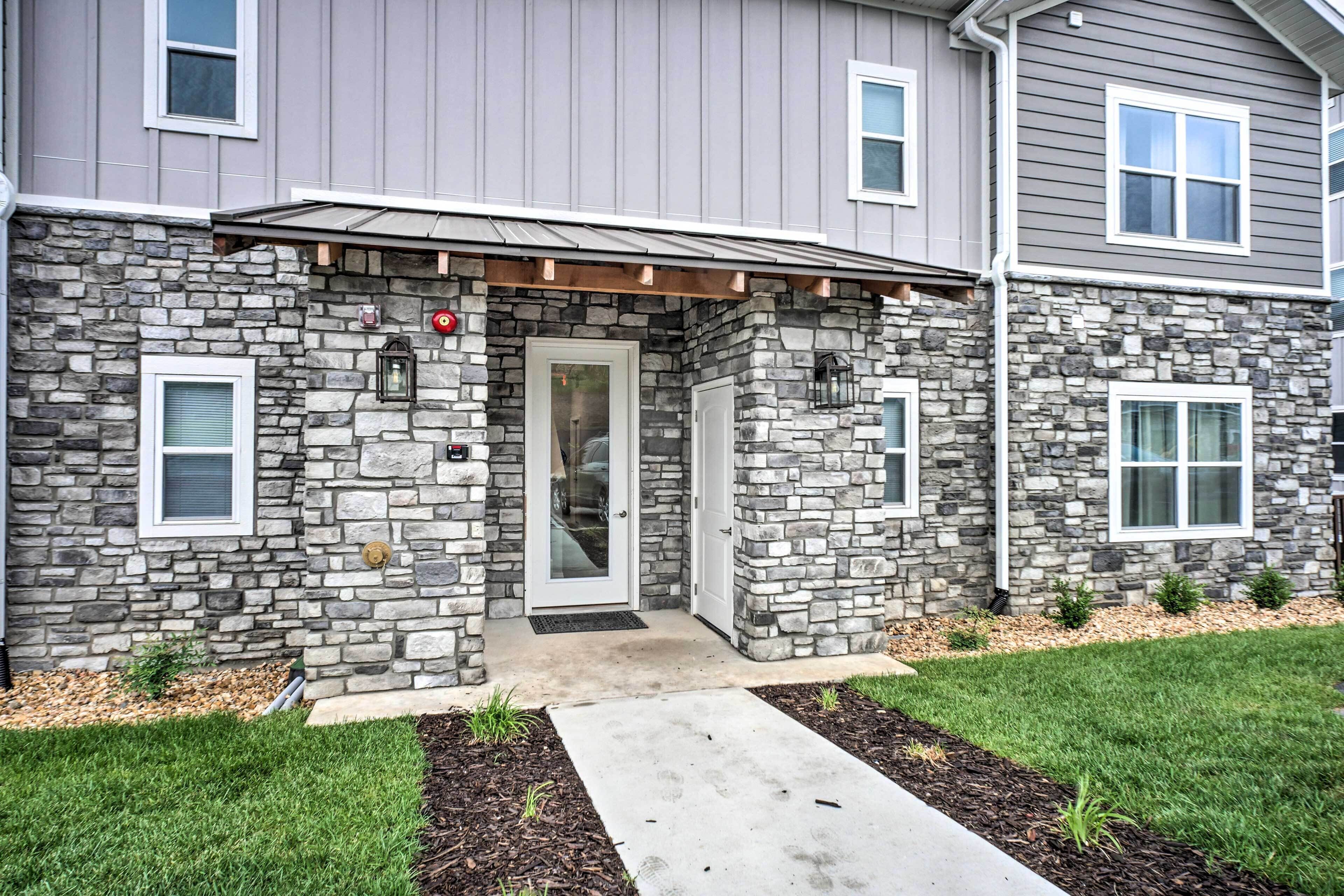 A two-story house with a stone facade, a front door with a glass panel, and a small porch area.