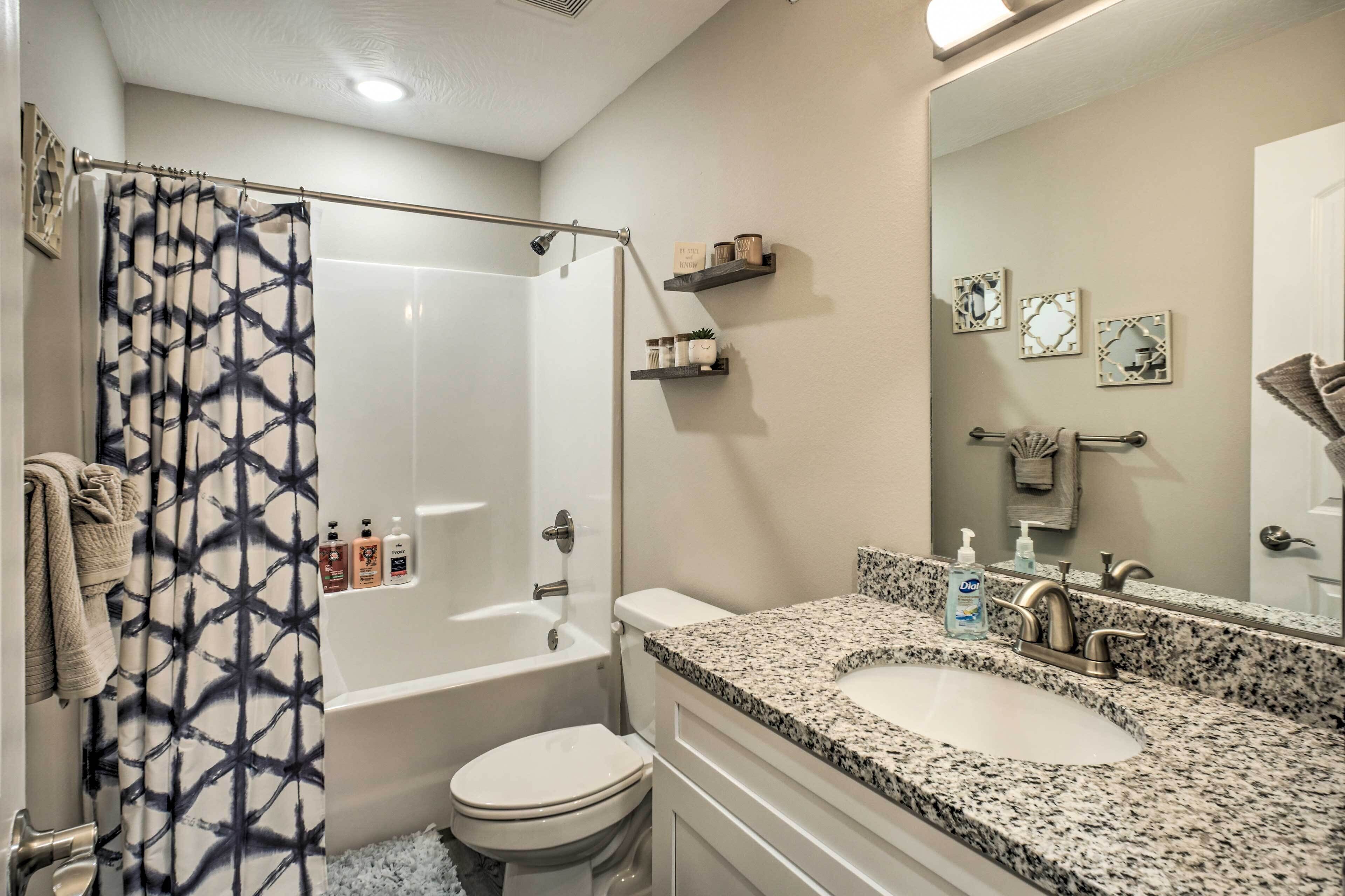 A bathroom with a shower, toilet, sink, and a mirror.