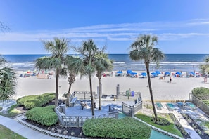 A beach view with palm trees, a pool area, and beach umbrellas.