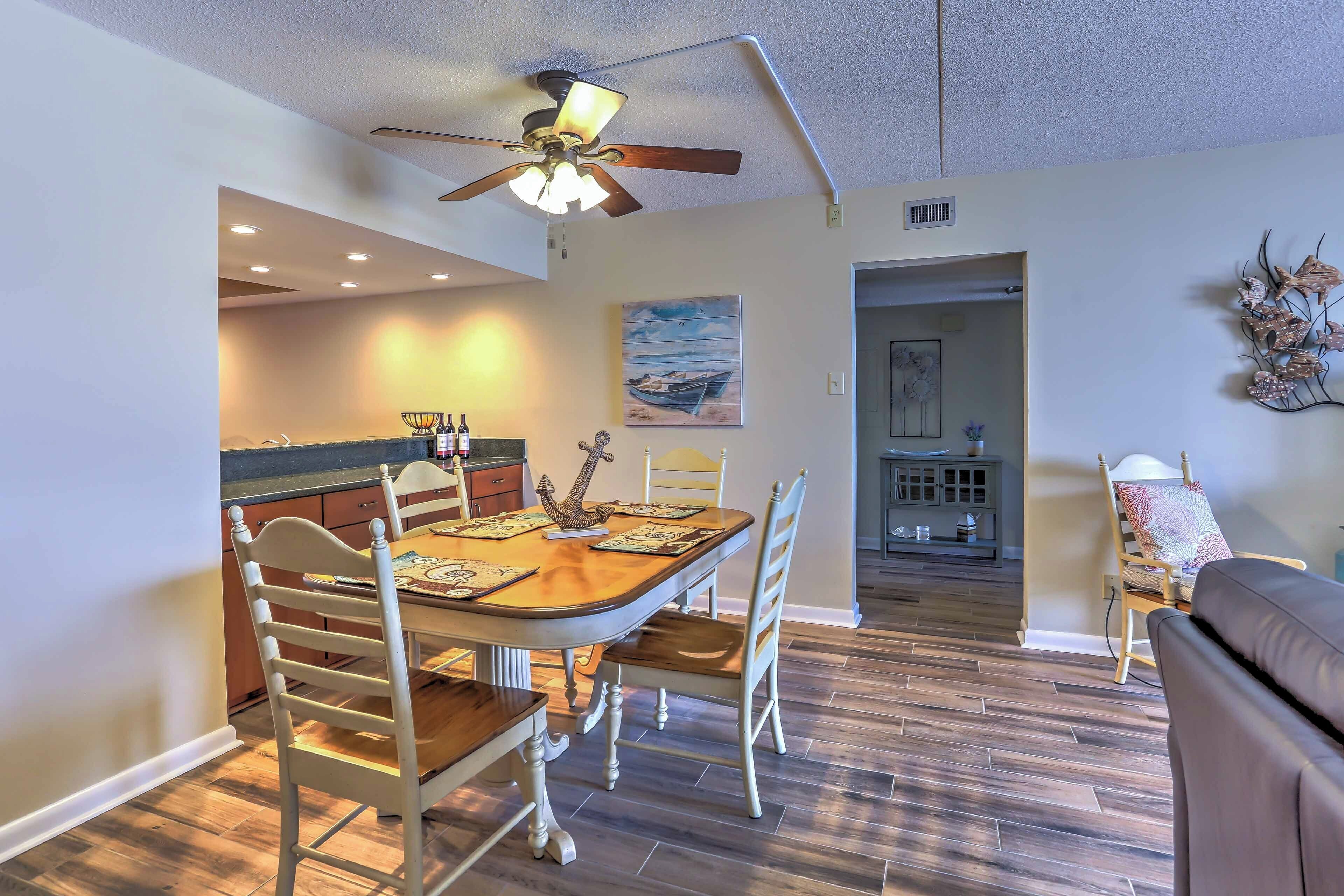 A dining area with a wooden table, white chairs, and a ceiling fan.