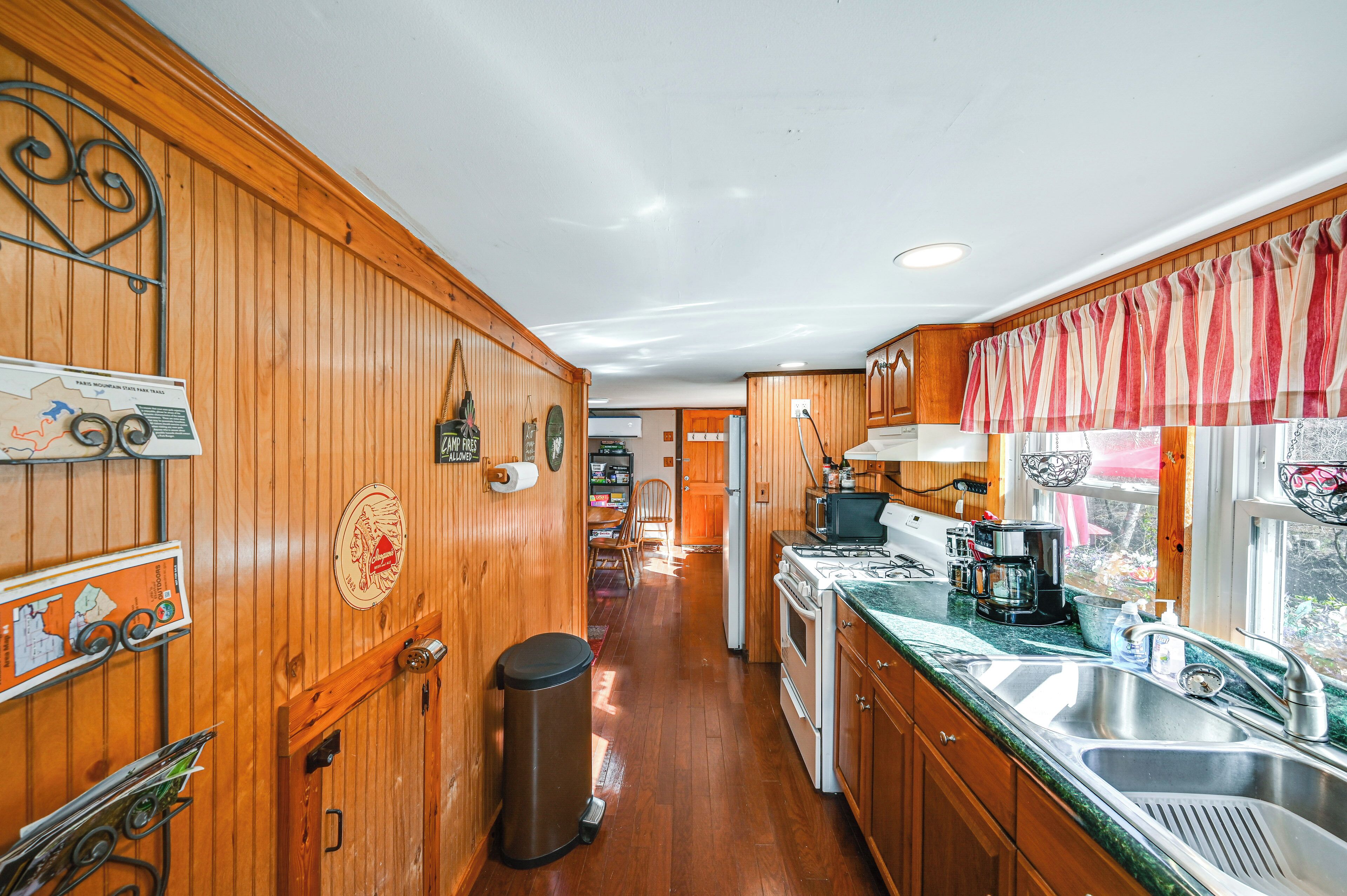 Una cocina con paredes de madera, un lavamanos de acero inoxidable y un microondas.