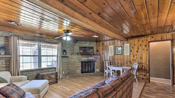 Ein gemütliches Blockhaus-Interieur mit Kamin aus Stein, Holzboden und einem karierten Sofa.