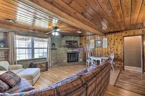 Un intérieur de chalet chaleureux avec une cheminée en pierre, un plafond en bois et un canapé à carreaux.