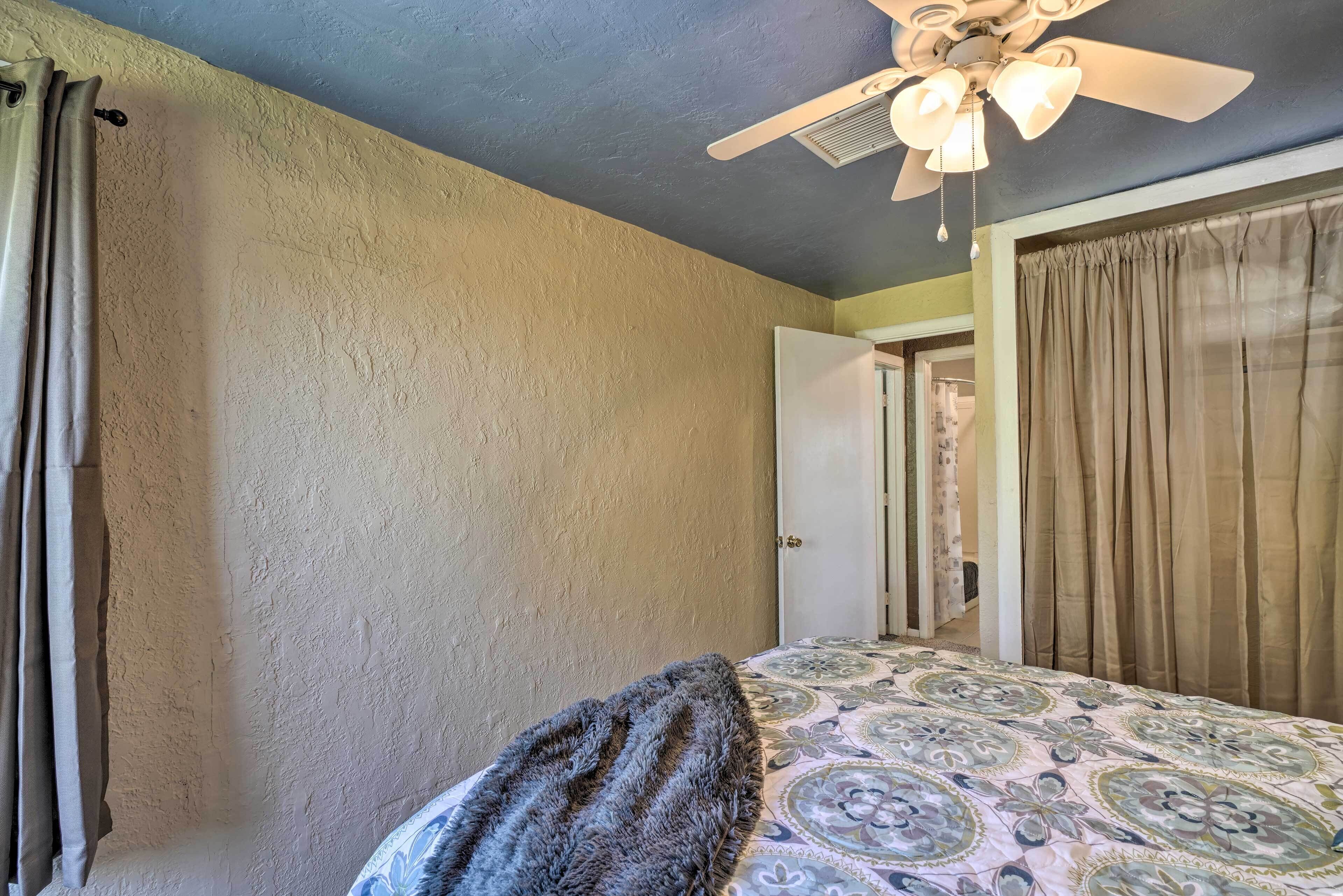 A bedroom with a bed, a ceiling fan, and a door leading to another room.