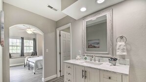 Une salle de bain avec un grand miroir, deux lavabos et un meuble-lavabo avec des tiroirs.