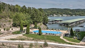 A lakeside property with a swimming pool, dock, and surrounding greenery. - Balcony & Seasonal Pool: Lakefront Ozark Condo (Camdenton)