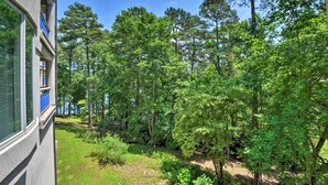 A building with a balcony overlooking a dense forest and a body of water. - Condo on Lake Keowee w/ Resort Amenities & Pool! (Salem)