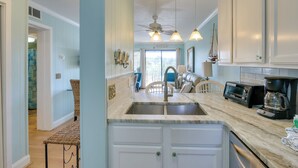 A kitchen with a marble countertop, a built-in sink, a ceiling fan, and a view of the outside. - Pool, Sauna & Beach Access: Hilton Head Condo (Hilton Head Island)