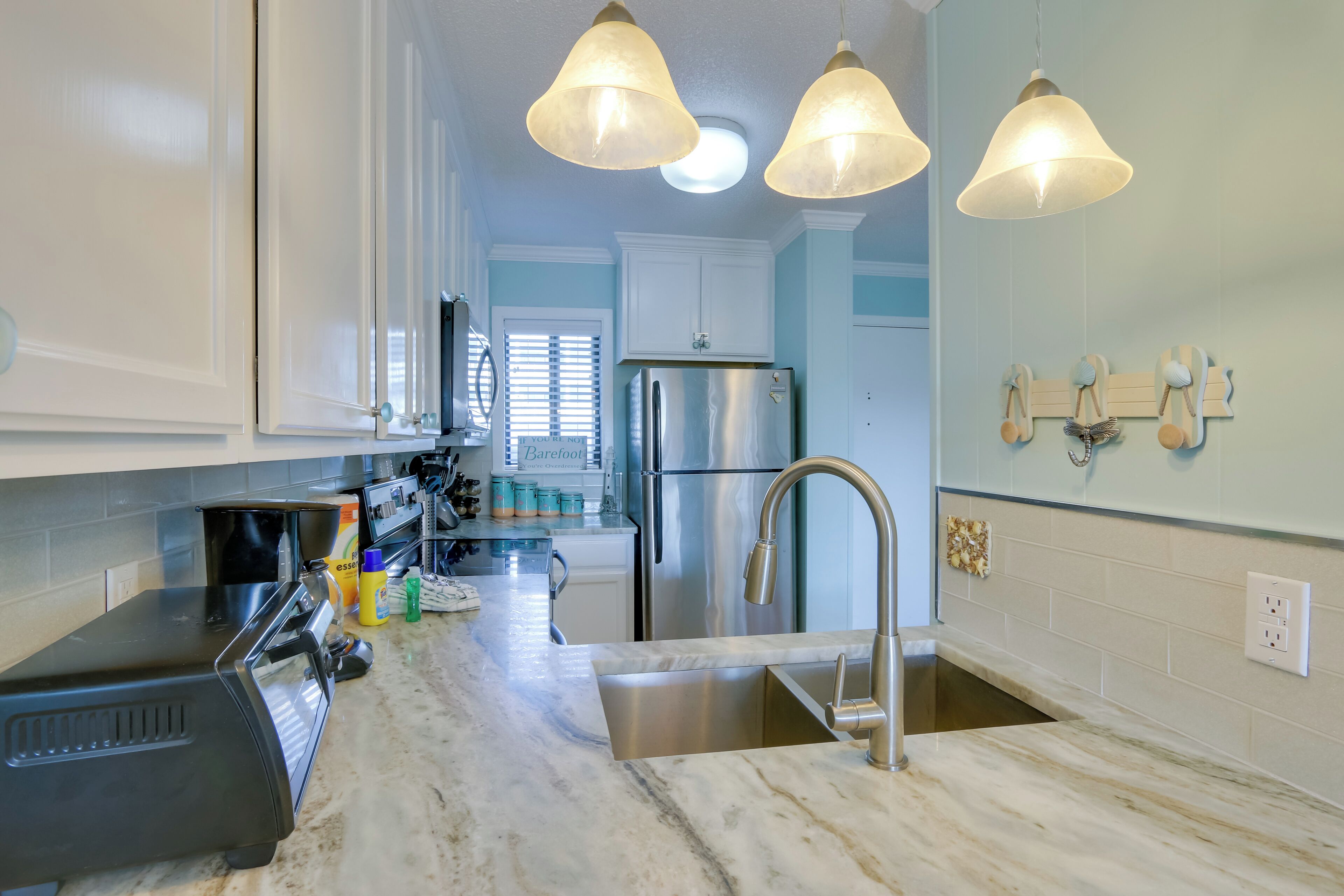 A kitchen with a stainless steel refrigerator, a sink, and a countertop with various appliances and items.