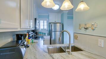 A kitchen with a stainless steel refrigerator, a sink, and a countertop with various appliances and items.