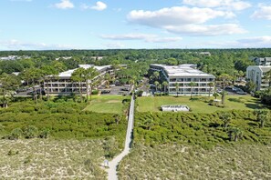 Ein moderner Gebäudekomplex mit mehreren Stockwerken, umgeben von üppiger Vegetation und wolkenlosem Himmel.