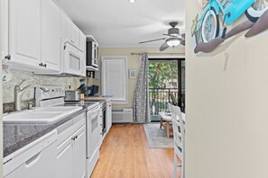 Eine Küche mit weißen Schränken, einer Granit-Arbeitsplatte und einem Deckenventilator.