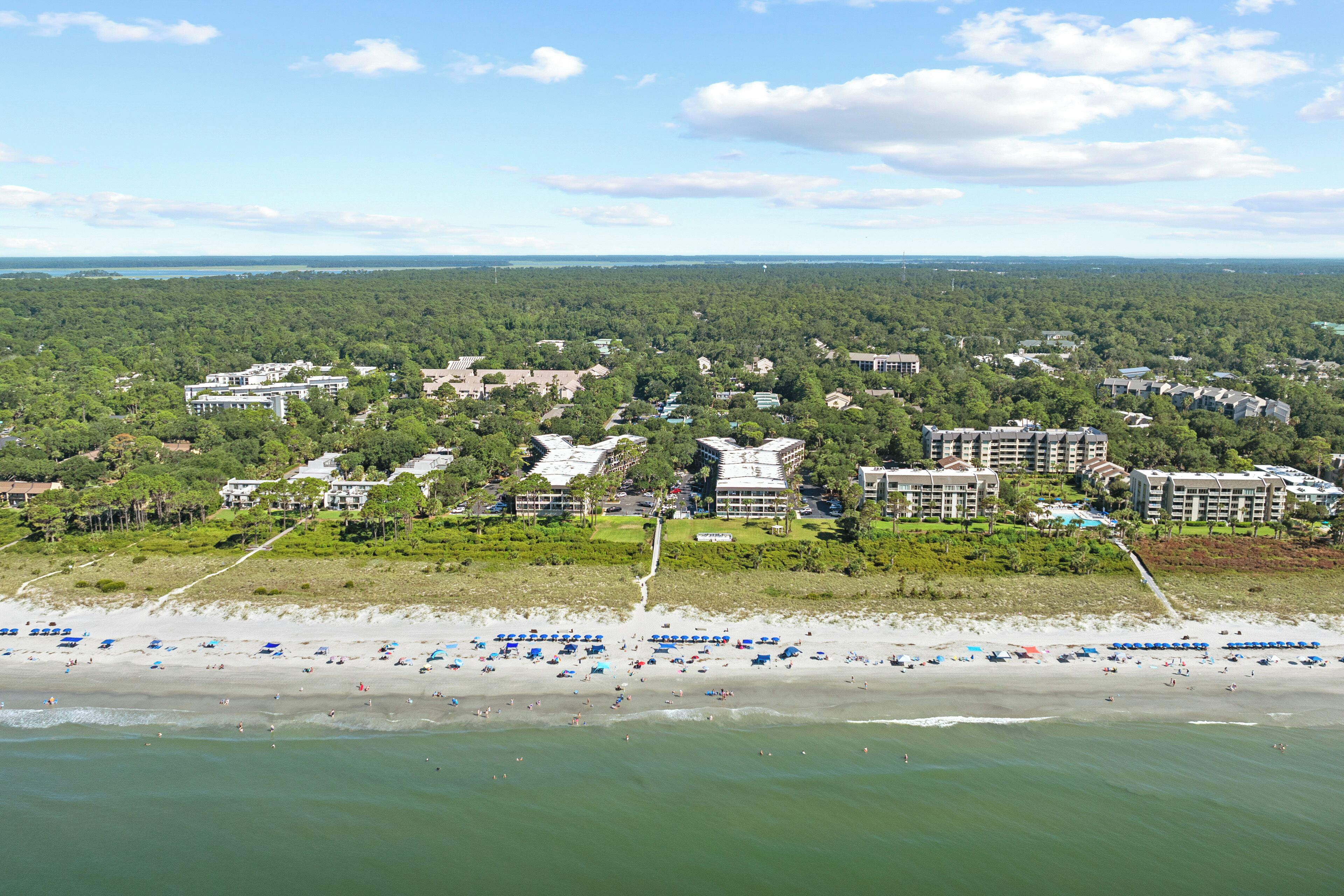 A coastal resort with multiple buildings, a sandy beach, and a view of the ocean.