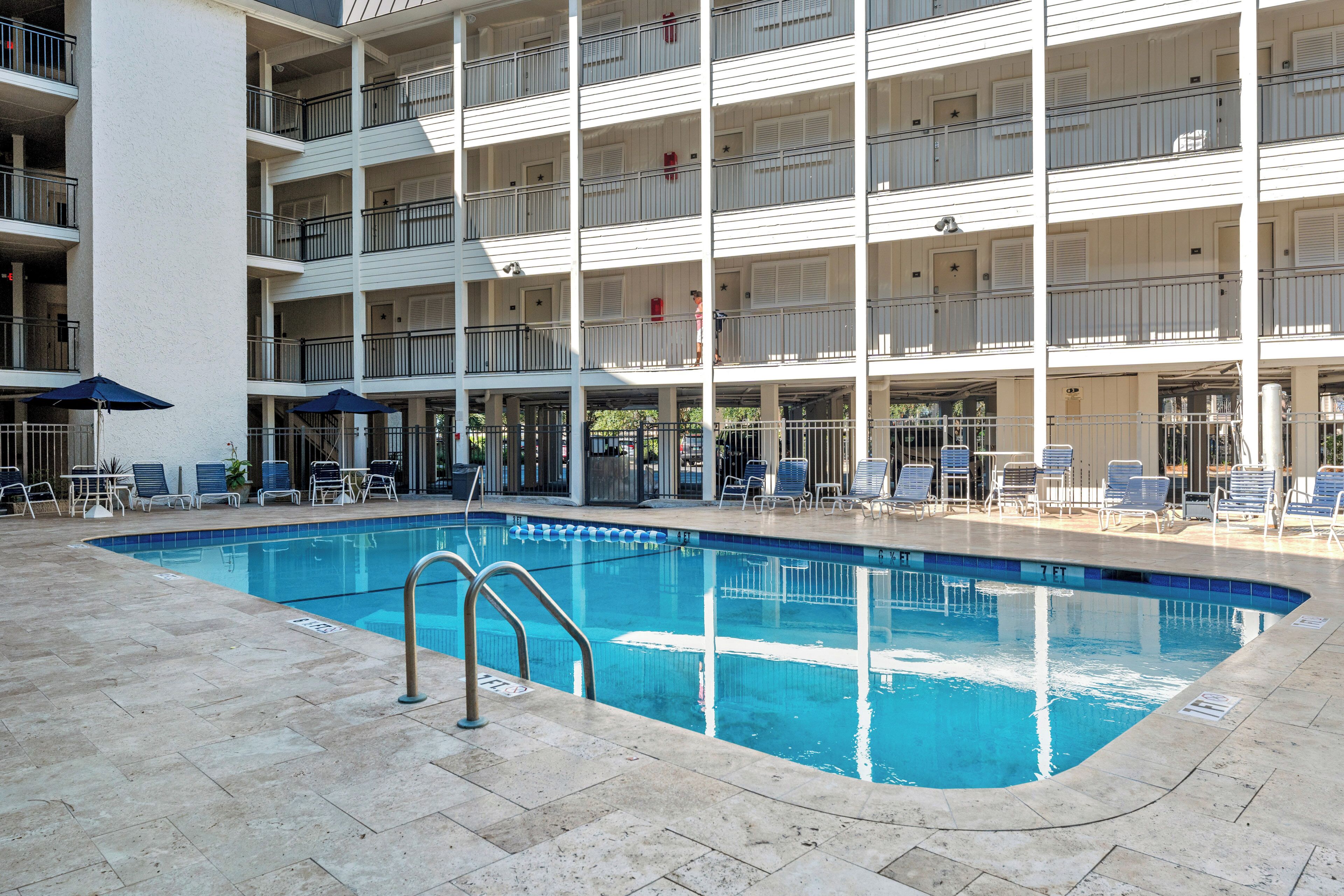 A multi-story hotel with a swimming pool, outdoor seating, and balconies.