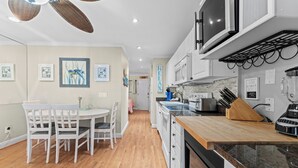 Une cuisine moderne avec des meubles blancs, un plan de travail en bois et un coin repas avec des chaises blanches.