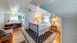 A bedroom with a large bed, a smaller bed, wooden flooring, a ceiling fan, and a window. - Cozy Augusta Home w/ Porch: Walk to Katy Trail! (Augusta)