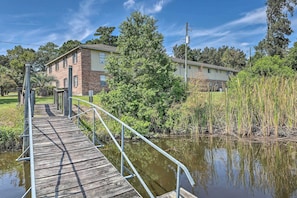 A wooden bridge leading to a building with a brick facade, surrounded by greenery and a body of water. - Cozy Hanahan Condo w/ Cooper River Access! (Hanahan)