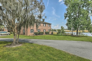 A brick building with a paved driveway and a grassy lawn. - Cozy Hanahan Condo w/ Cooper River Access! (Hanahan)