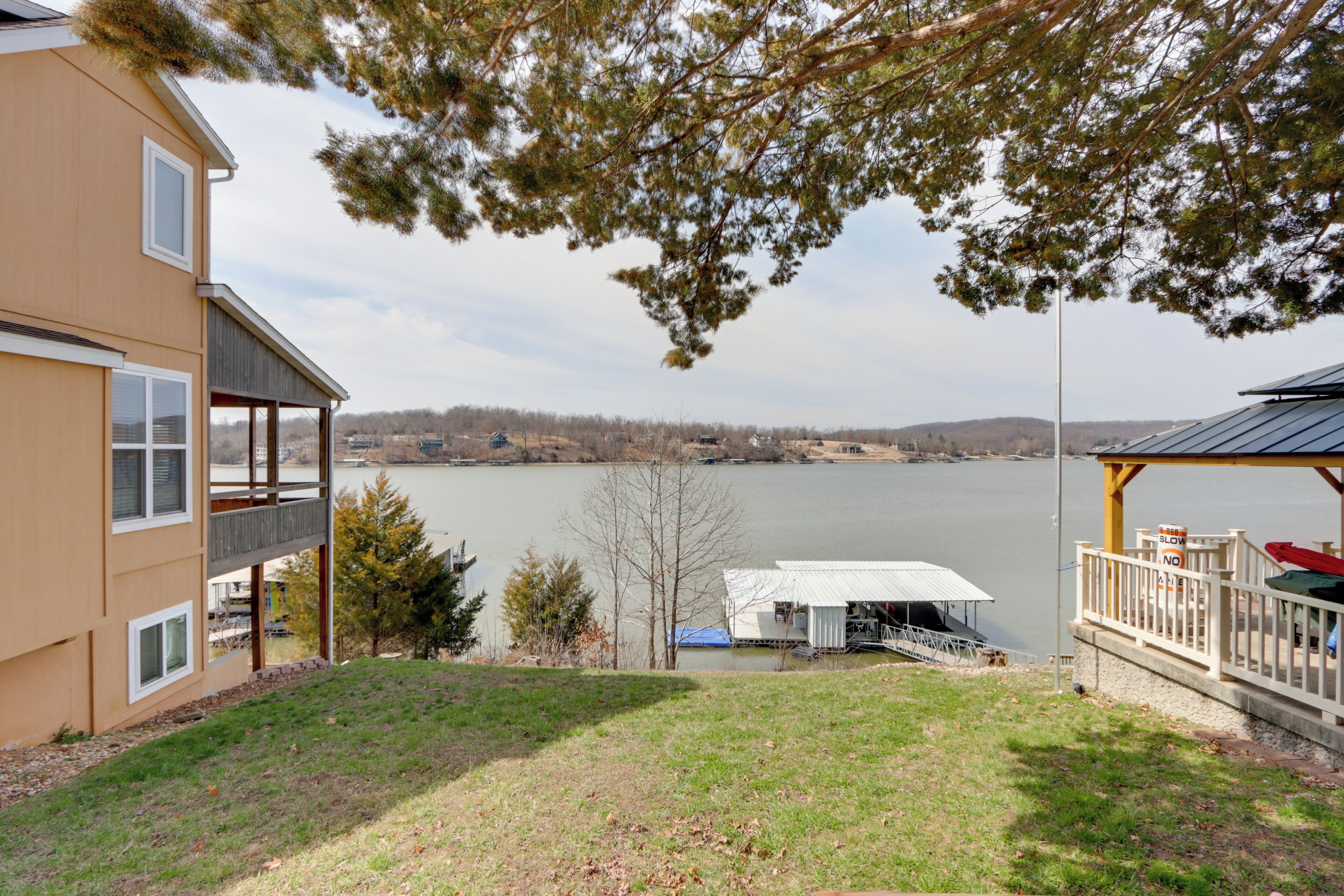 A lakeside property with a deck, a covered area, and a view of the lake.