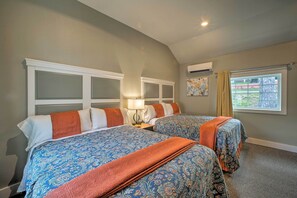 Quarto de hotel com duas camas, janela com vista e ar condicionado.