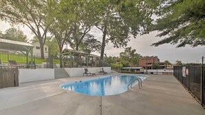Ein Schwimmbecken mit Liegestühlen und einer überdachten Sitzgelegenheit.