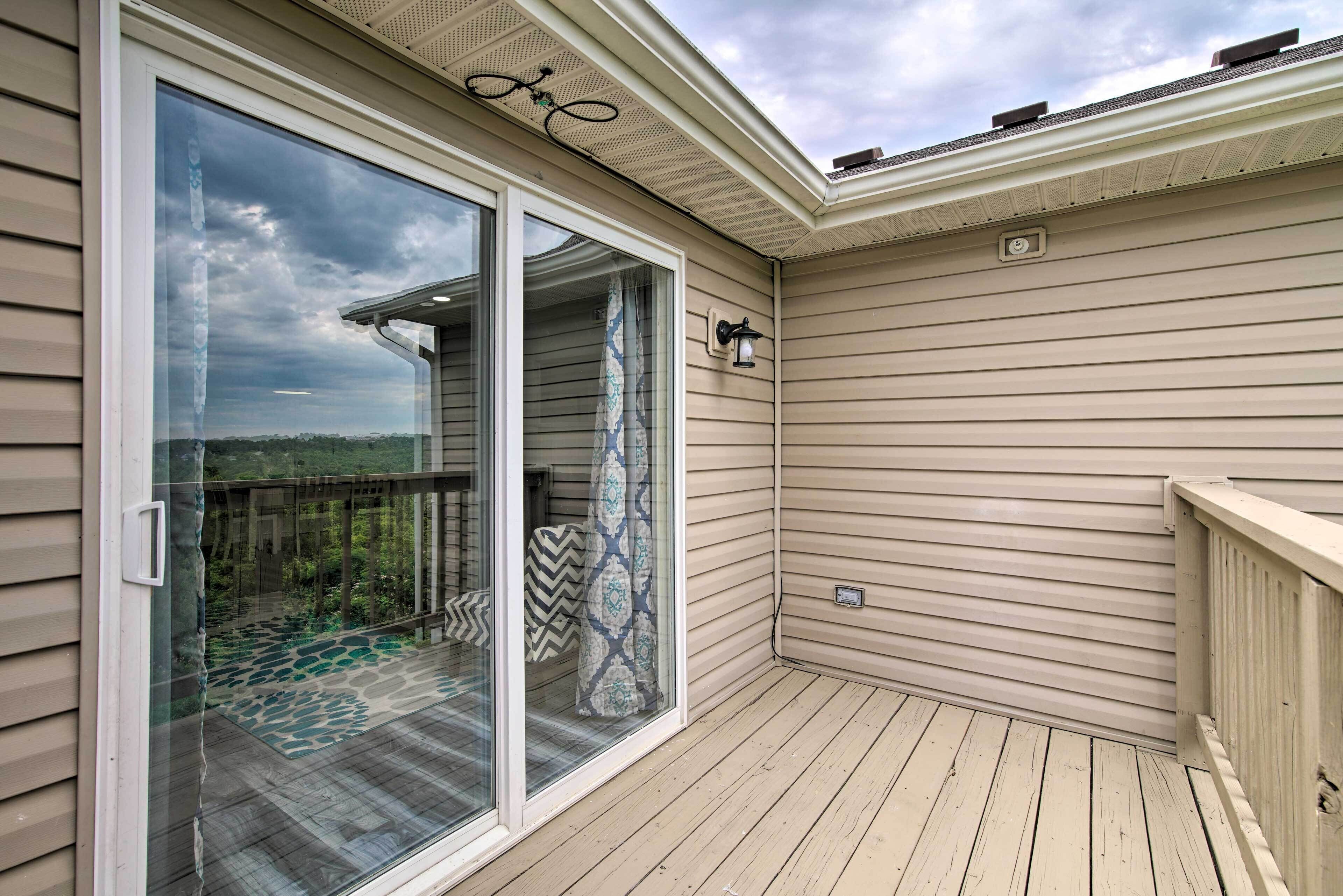 A covered deck with a glass door leading to a patio area.