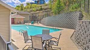 A swimming pool with a stone wall and a view of a blue building in the background.