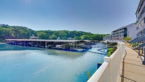 A waterfront hotel with a covered dock area, a pool, and a view of the surrounding greenery. - Pool + Boat Slip Available: Osage Beach Condo! (Osage Beach)