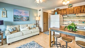 A cozy living room with a sofa, a dining area with stools, and a kitchen with wooden cabinets and a refrigerator. - Pool + Boat Slip Available: Osage Beach Condo! (Osage Beach)