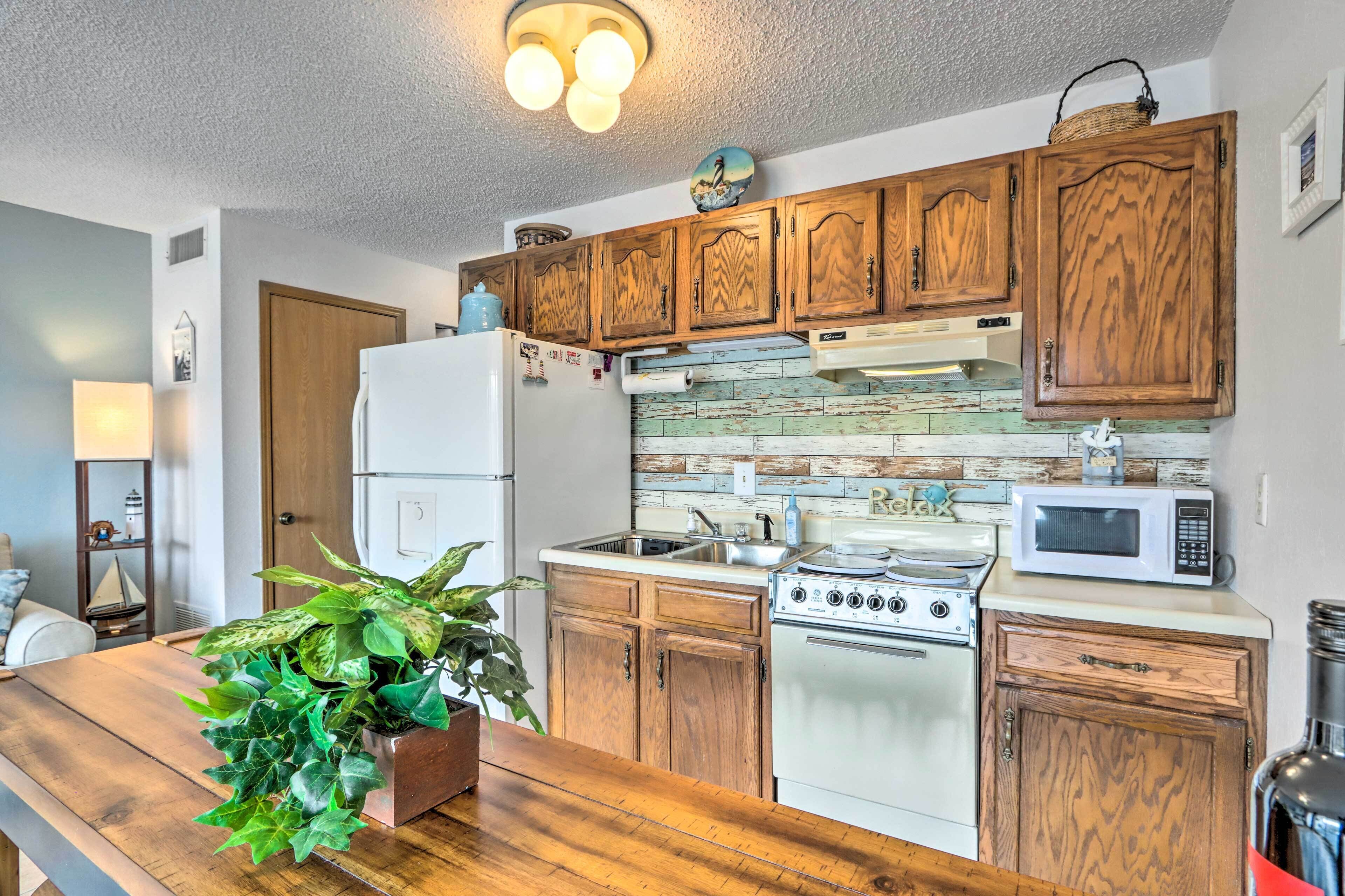 A kitchen with wooden cabinets, a white refrigerator, a stove, a microwave, and a sink.