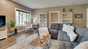 A living room with a grey sectional sofa, a wooden coffee table, a TV, and a large window. - Waterfront Home Near Mark Twain National Forest (Poplar Bluff)