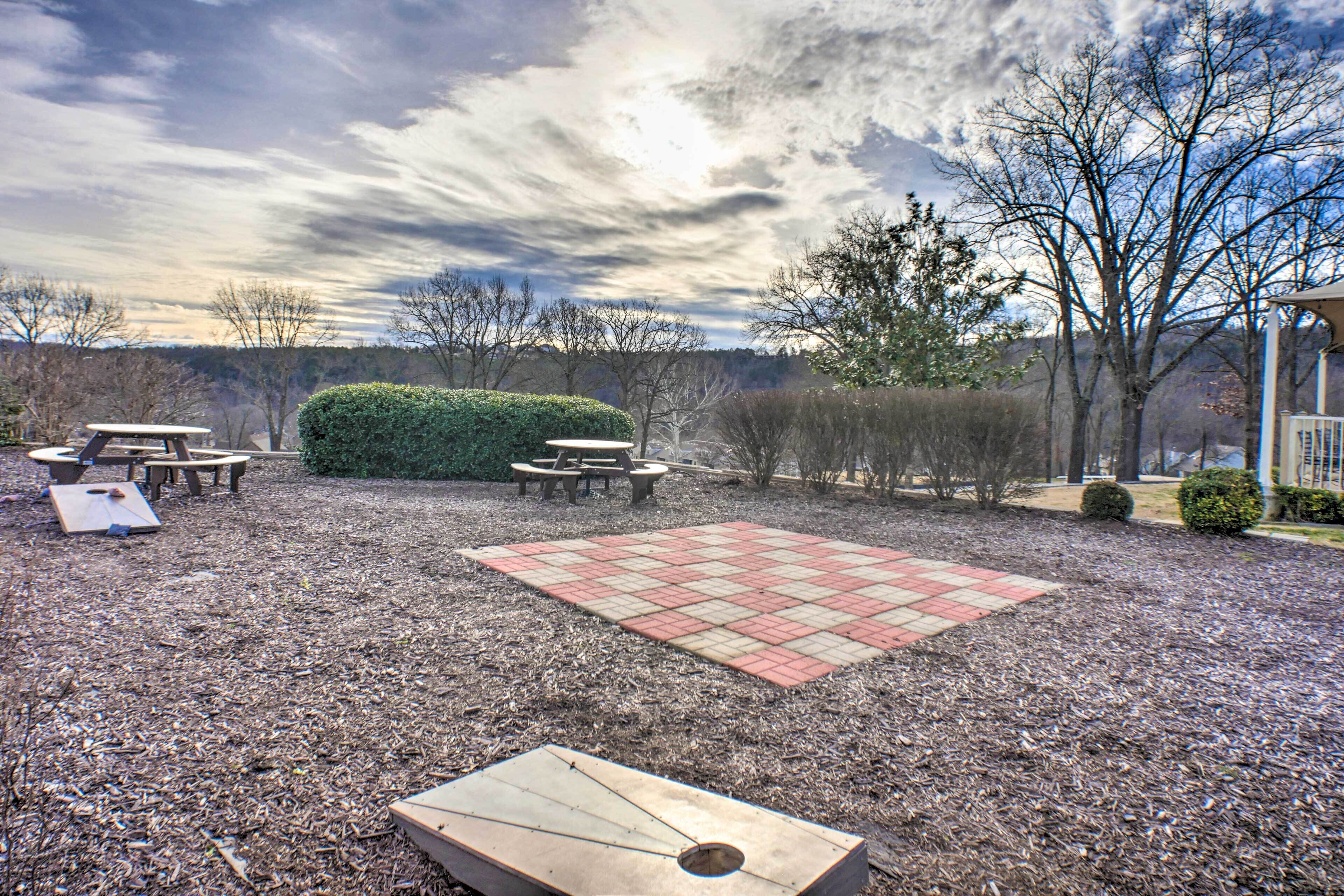 An outdoor patio area with picnic tables, a fire pit, and a red and beige checkered area.