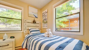 A bedroom with a bed, a nightstand, a window, and a view of a building outside. - Cozy Table Rock Lake Vacation Rental w/ Deck (Golden)