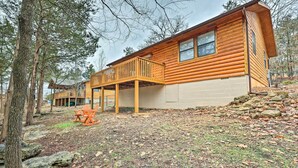 A log cabin with a deck, surrounded by trees and a rocky ground. - Cozy Table Rock Lake Vacation Rental w/ Deck (Golden)