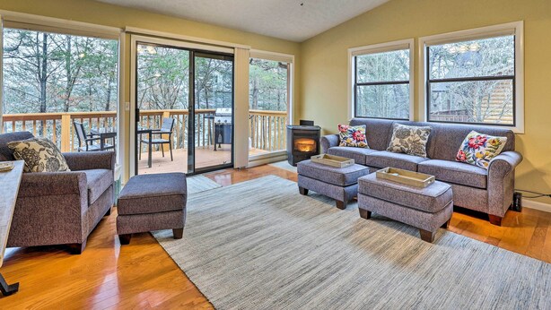 A cozy living room with a fireplace, large windows, and a sliding glass door leading to a deck. - Cozy Table Rock Lake Vacation Rental w/ Deck (Golden)