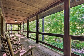 A wooden deck with a ceiling fan, wooden railings, and a view of a forest. - Creekside Marietta Cabin Retreat w/ Fire Pit! (Marietta)