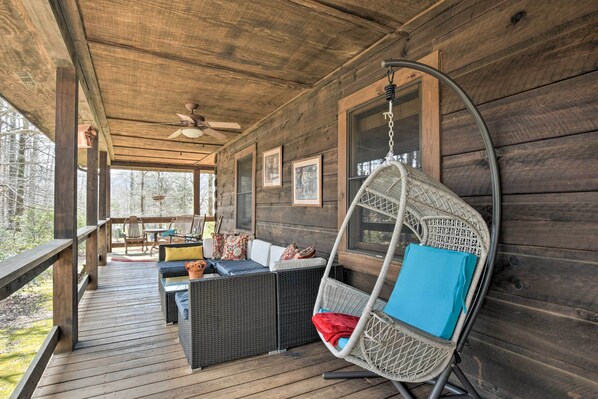 A wooden deck with wicker furniture and a hanging chair.