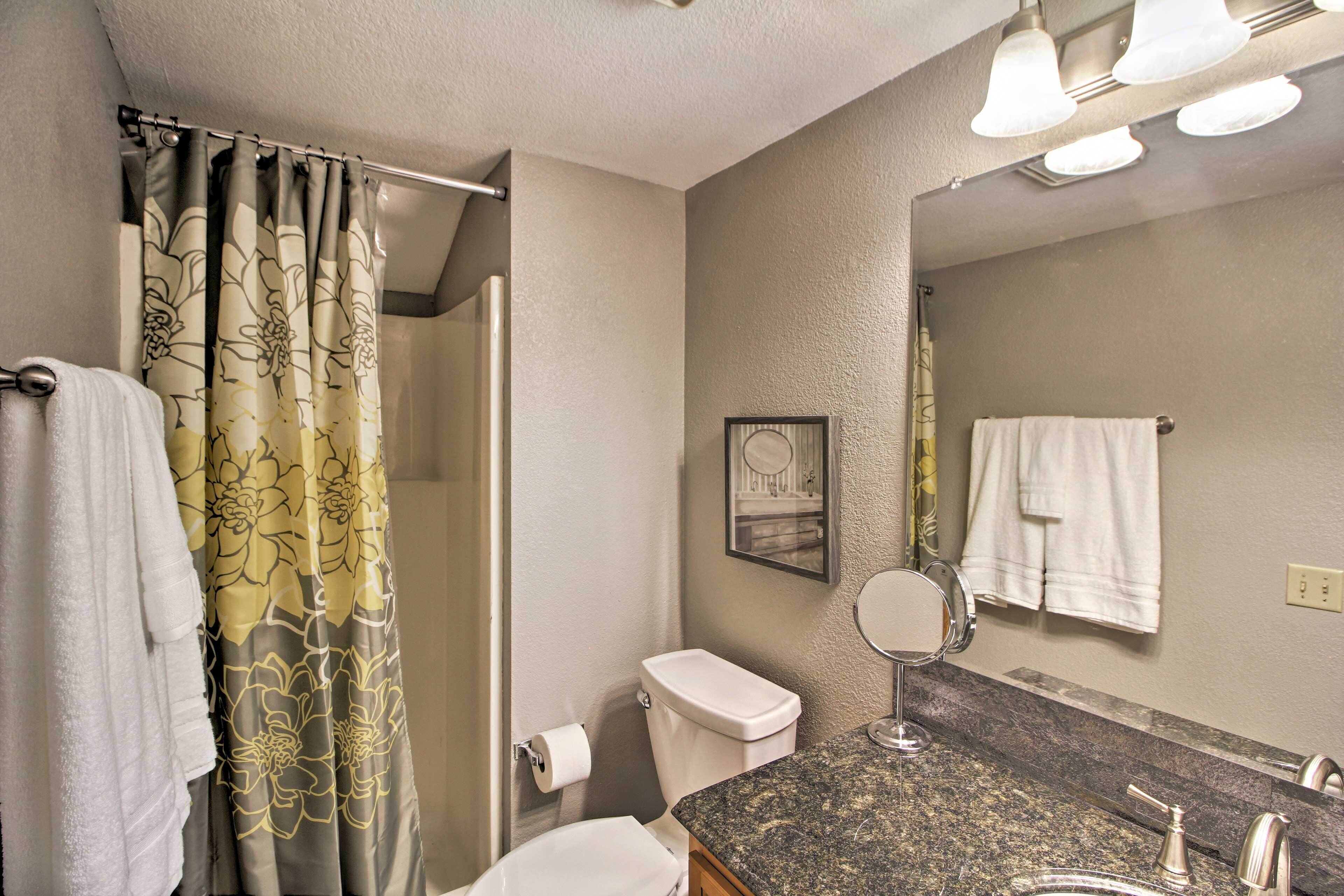 A bathroom with a shower curtain, toilet, sink, mirror, and towel rack.