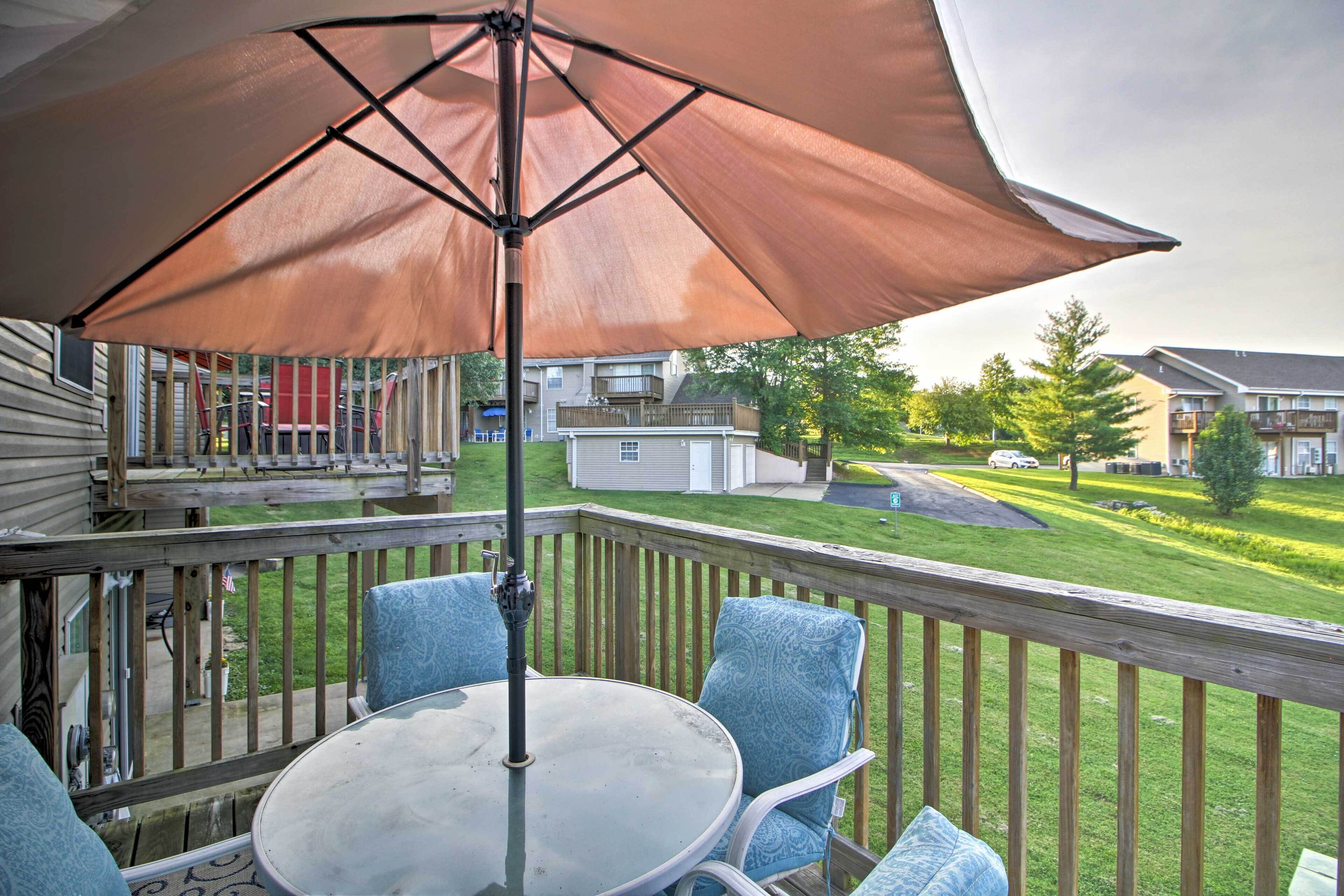 A deck with a table and chairs, an umbrella, and a view of a residential area.