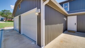 A two-car garage with a white door and a light fixture above it. - Delightful Townhouse w/ Patio & Shared Yard! (Kimberling City)