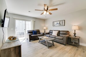 Ein Wohnzimmer mit Deckenventilator, zwei Sofas, einem Couchtisch und einem Fernseher auf einem Standfuß.